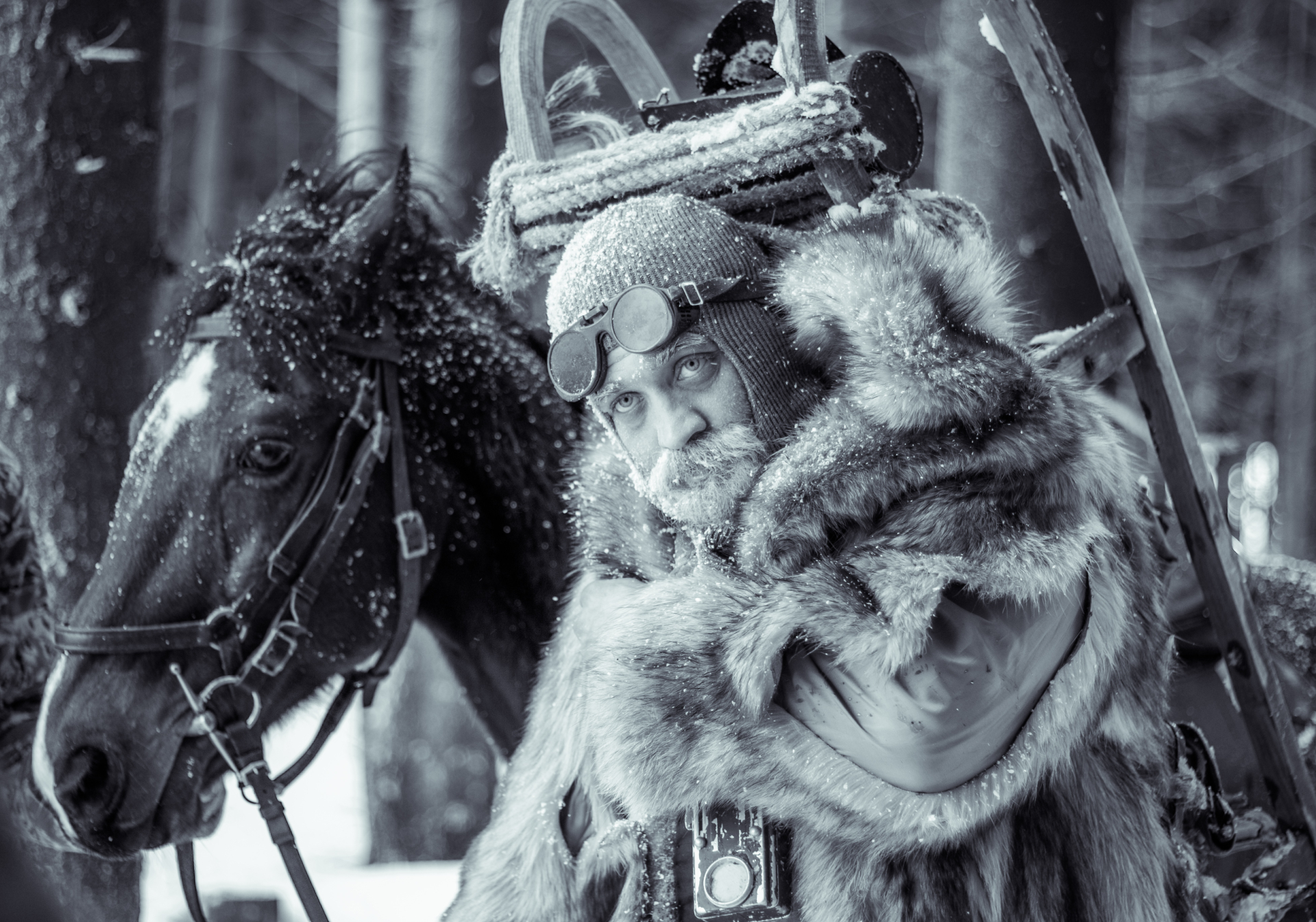 Portrait of a fur-clad character beside a horse in winter